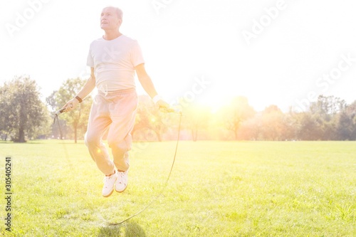 Determined senior man working out with skipping rope in park