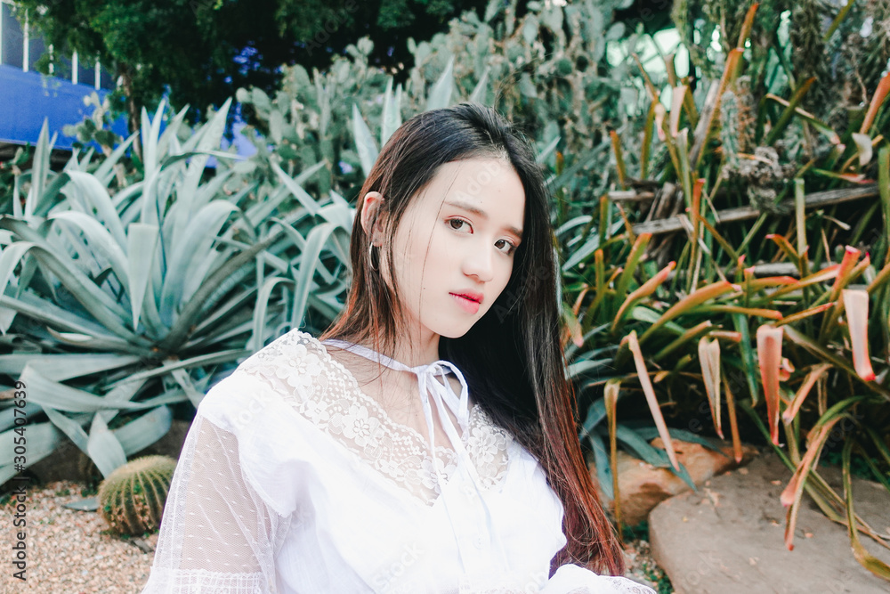 Young beautiful asian woman in white dress posting with cactus and succulent plants background Young beautiful asian woman in white dress posting with cactus and succulent plants background
