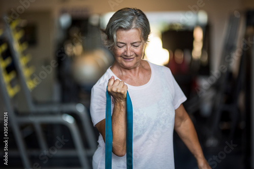 mature woman alone at the gym doing exercises with an elastic - healthy and fitness lifestyle and concept - senior or pensioner working her healthy photo