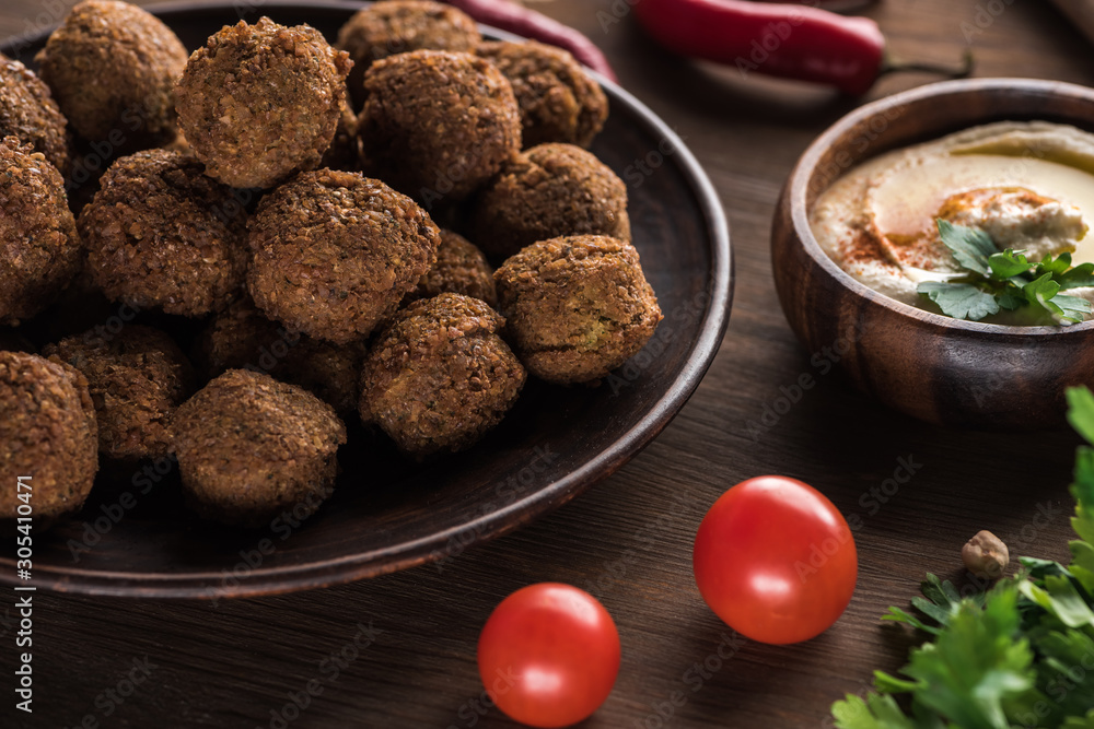 close up view of falafel balls near hummus on wooden table close up view of falafel balls near hummus on wooden table
