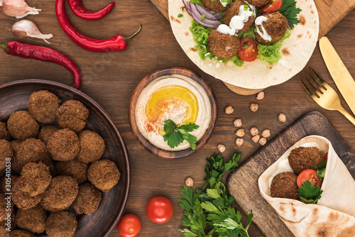 top view of falafel with vegetables and hummus on wooden table
