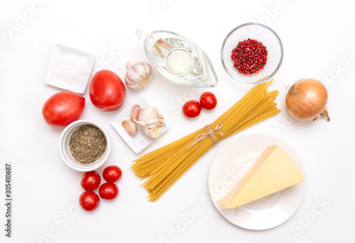pasta, raw spaghetti, piece of cheese, vegetable oil, garlic, onion, spices, tomatoes on white background