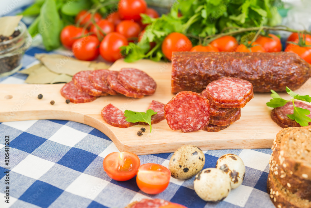 Sliced salami with cherry tomatoes and quail eggs on table