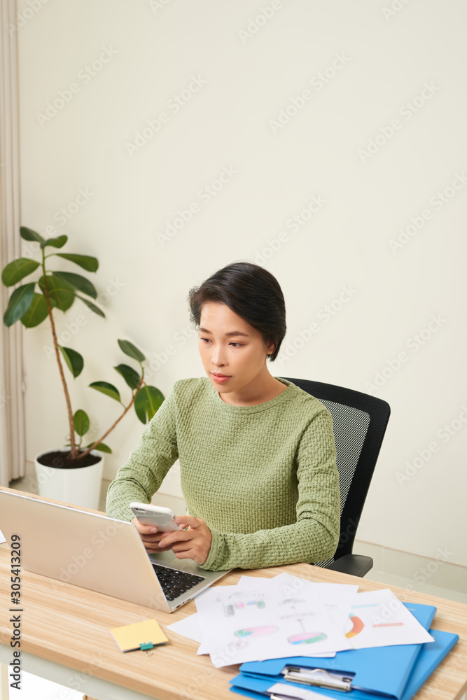 Young Asian businesswoman holding mobile phone to handle her working Young Asian businesswoman holding mobile phone to handle her working