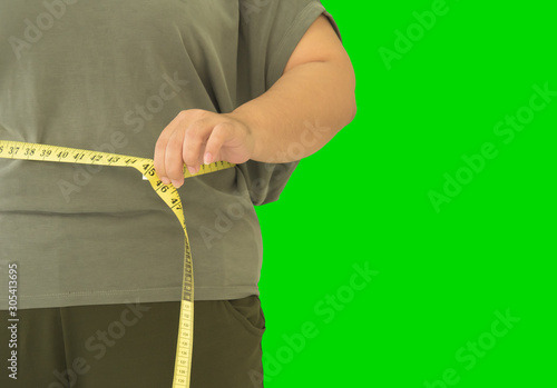 Fat woman is measuring the width of her waist.