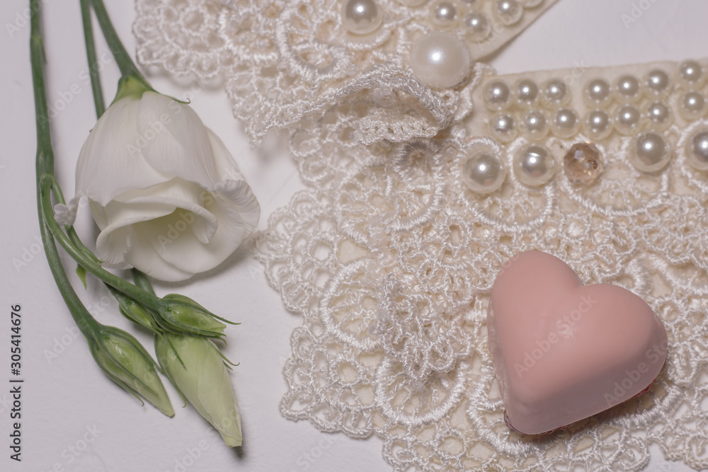 White lysanthus flower on a white background with lace and chocolate in the form of a heart White lysanthus flower on a white background with lace and chocolate in the form of a heart