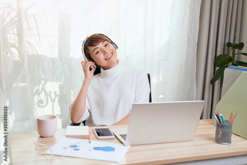 Young Asian woman in headphones working on the computer at home Young Asian woman in headphones working on the computer at home
