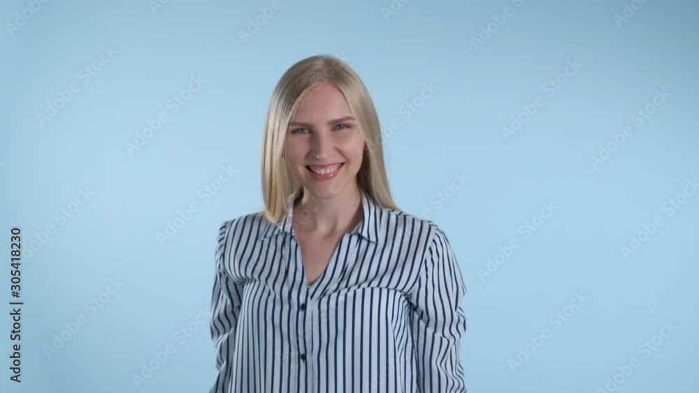 Pleasant-looking woman turning around and smiling to the camera. Blue background. Pleasant-looking woman turning around and smiling to the camera. Blue background.