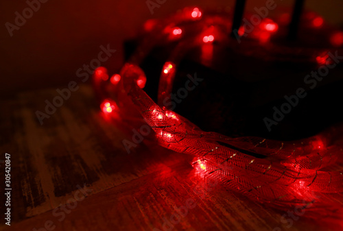 Bright red New Year and Christmas rice lights, shallow depth of field. Abstract red light background. Decorative flashing lights, ornaments to christmas celebration, holiday scene. Christmas concept.