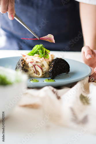 A chef is decorating a salad. Seaweed Salad