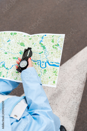 selective focus of woman holding map and compass on street © LIGHTFIELD STUDIOS