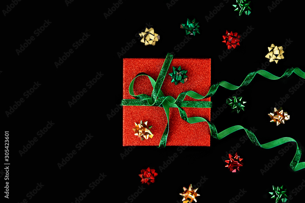 Fototapeta premium Golden, green and and red bows around box set for gift wrap. Christmas gift, standing geometry. Funny minimal flat lay composition. Happy holiday Valentine's Day layout. New year neo preparation