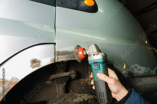 The repairman will repair the damaged car. Working with a tool grinder to clean the rust of a metal