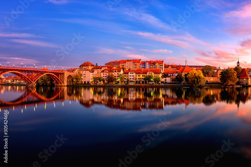 Amazing view of Maribor Old city, Main bridge (Stari most) on the Drava river before sunrise, Slovenia. Scenic cityscape with sky and reflection, travel background for wallpaper or guide book