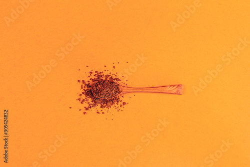 wooden spoon with instant granulated coffee on a background of neo carrot color top view, minimal art