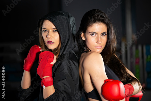 Two beautiful female boxer in the gym at night preparing for a fight