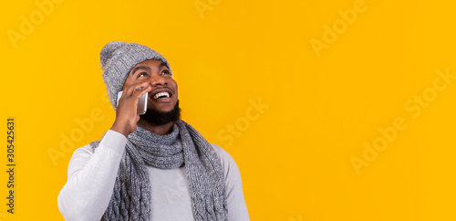 Happy black man talking by phone, looking at free space © Prostock-studio