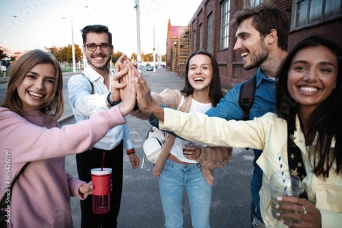 Group of friends stacking hands outdoor - Happy young people having fun joining and celebrating together