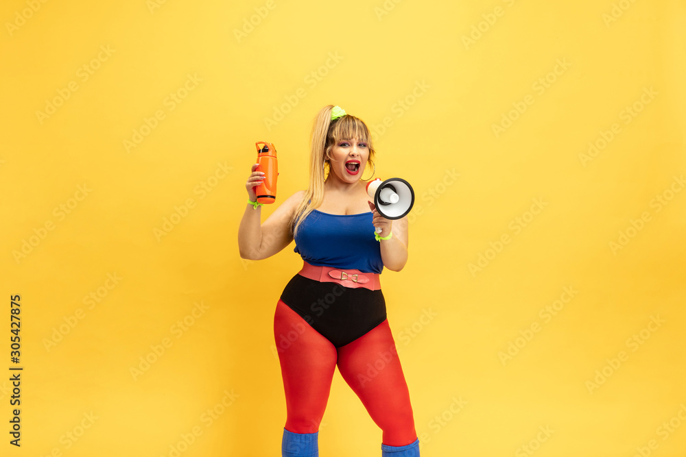 Young caucasian plus size female model's training on yellow background. Stylish woman in bright clothes. Copyspace. Concept of sport, healthy lifestyle, body positive, fashion. Calling in mouthpeace. Young caucasian plus size female model's training on yellow background. Stylish woman in bright clothes. Copyspace. Concept of sport, healthy lifestyle, body positive, fashion. Calling in mouthpeace.