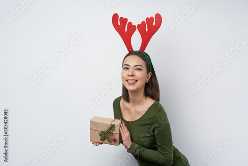 Happy girl holding a gift box wrapped in craft paper with a branch of fir tree