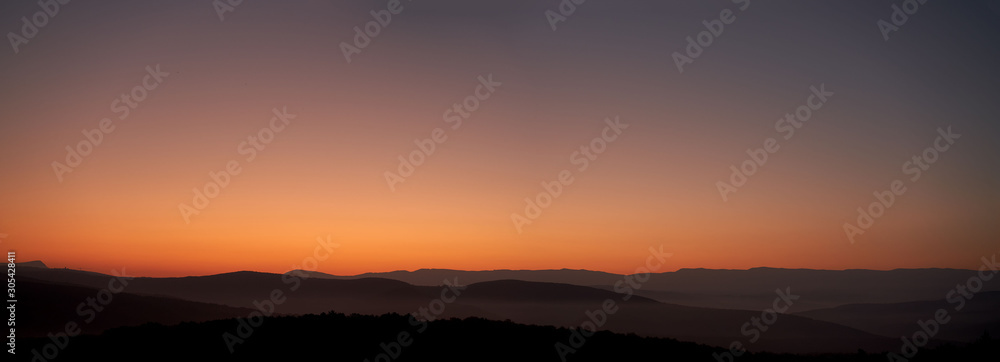 Obraz premium Panoramic view of the predawn twilight. A good view of the low mountain ranges under the transparent morning fog.
