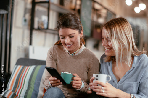 Best friends. Two beautiful woman sitting on sofa. Sisters at home © JustLife