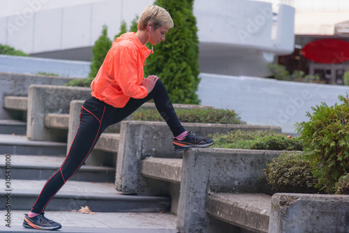 Young female runner prepairing for jogging in the city street. Fit body requires hard work. Urban sport concept. Young female exercising in sport clothes.