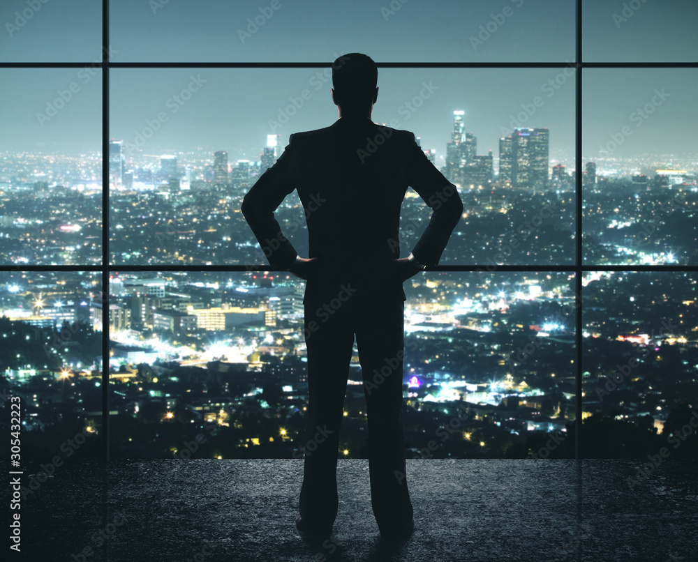 Fototapeta premium Businessman standing in night office