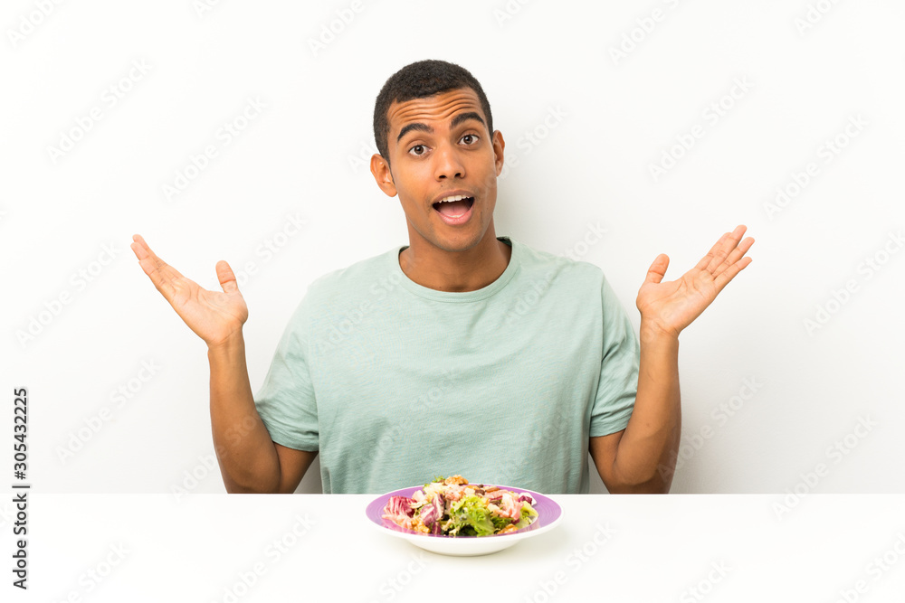 Young handsome man with salad in a table with surprise facial expression Young handsome man with salad in a table with surprise facial expression
