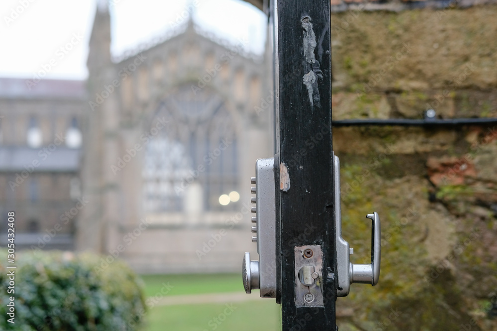 Shallow focus of an opened park door showing a digital type, combination lock, allowing members of the public access to a large Cathedral seen out of focus in the background. Shallow focus of an opened park door showing a digital type, combination lock, allowing members of the public access to a large Cathedral seen out of focus in the background.