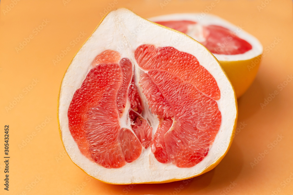 Fresh grapefruit on an orange background, close-up. Sex concept. The concept of women's health Fresh grapefruit on an orange background, close-up. Sex concept. The concept of women's health