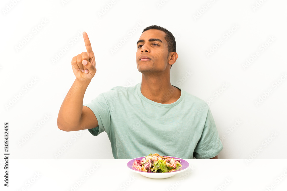Young handsome man with salad in a table touching on transparent screen Young handsome man with salad in a table touching on transparent screen