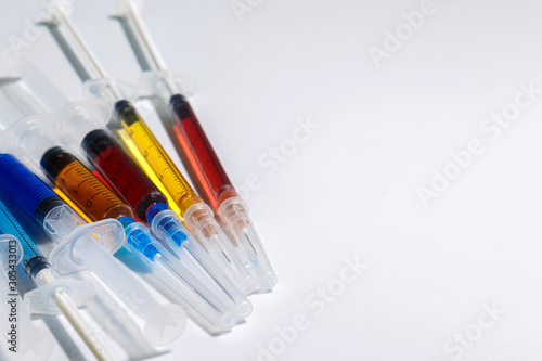 Medical syringes with colorful injections for cosmetology. Syringes with liquids of different colors on a light background.