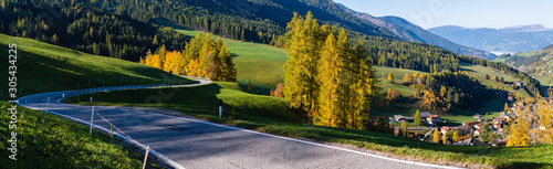 Light and shadows. Autumn Santa Magdalena Italy mountain village environs, grassy hills and secondary serpentine road. Picturesque traveling, seasonal and countryside beauty concept panorama view.