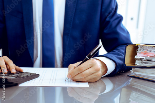 Bookkeeper or financial inspector hands making report, calculating or checking balance. Internal Revenue Service inspector man checking financial document. Business, tax and audit concepts