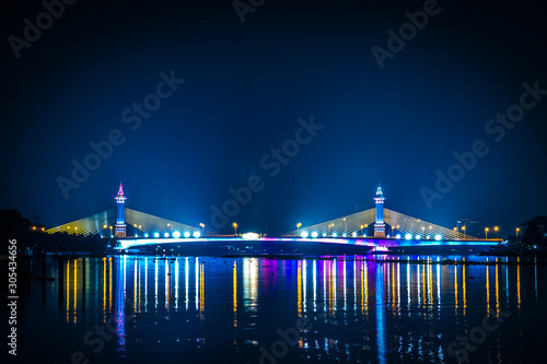 view of night scenery of city in Thailand with beautiful reflections of skyscrapers and bridges by riverside in twilight. Cityscape view of bridge crosses the Chao Phraya River