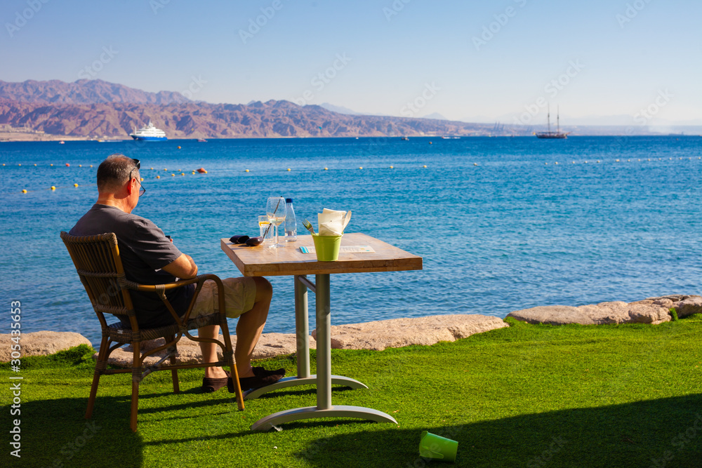 A middle-aged man staring at the sea by himself