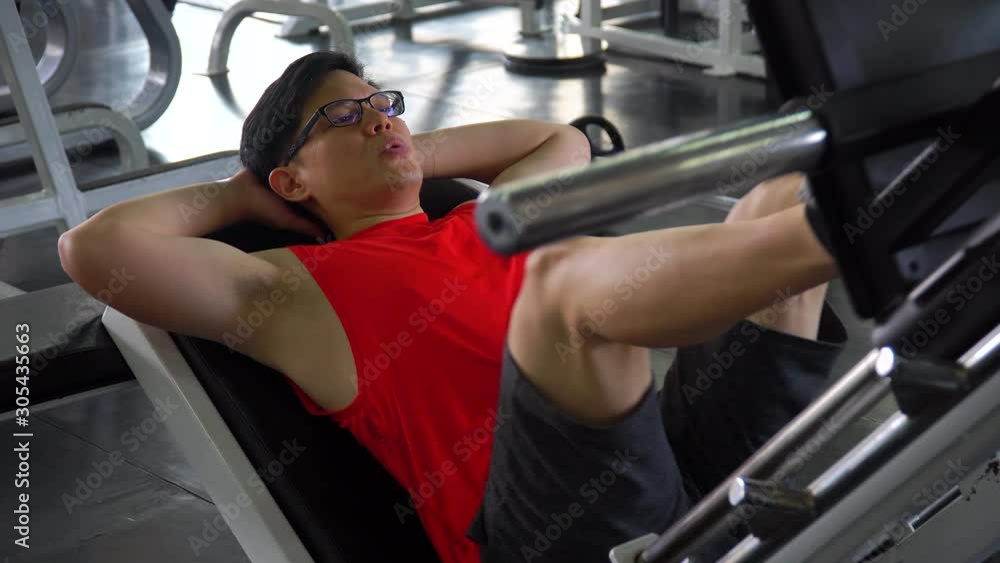 asian young sport man doing exercises with leg press machine in fitness gym . workout . training . Healthy lifestyle . indoor . handsome guy . effort . breathing hard asian young sport man doing exercises with leg press machine in fitness gym . workout . training . Healthy lifestyle . indoor . handsome guy . effort . breathing hard