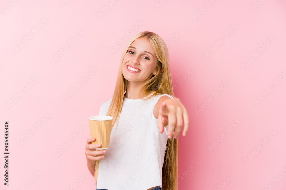 Young blonde girl holding a takeaway coffee cheerful smiles pointing to front. Young blonde girl holding a takeaway coffee cheerful smiles pointing to front.