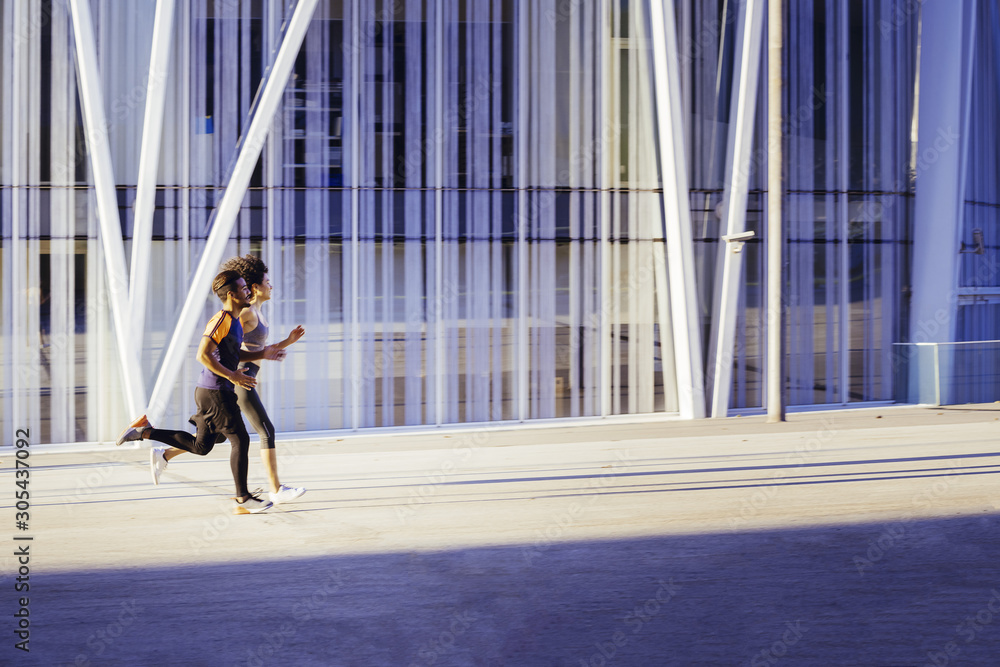 Fototapeta premium interracial couple running fast in the city street