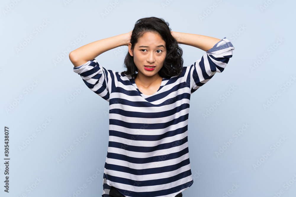 Asian young woman over isolated blue background frustrated and takes hands on head Asian young woman over isolated blue background frustrated and takes hands on head