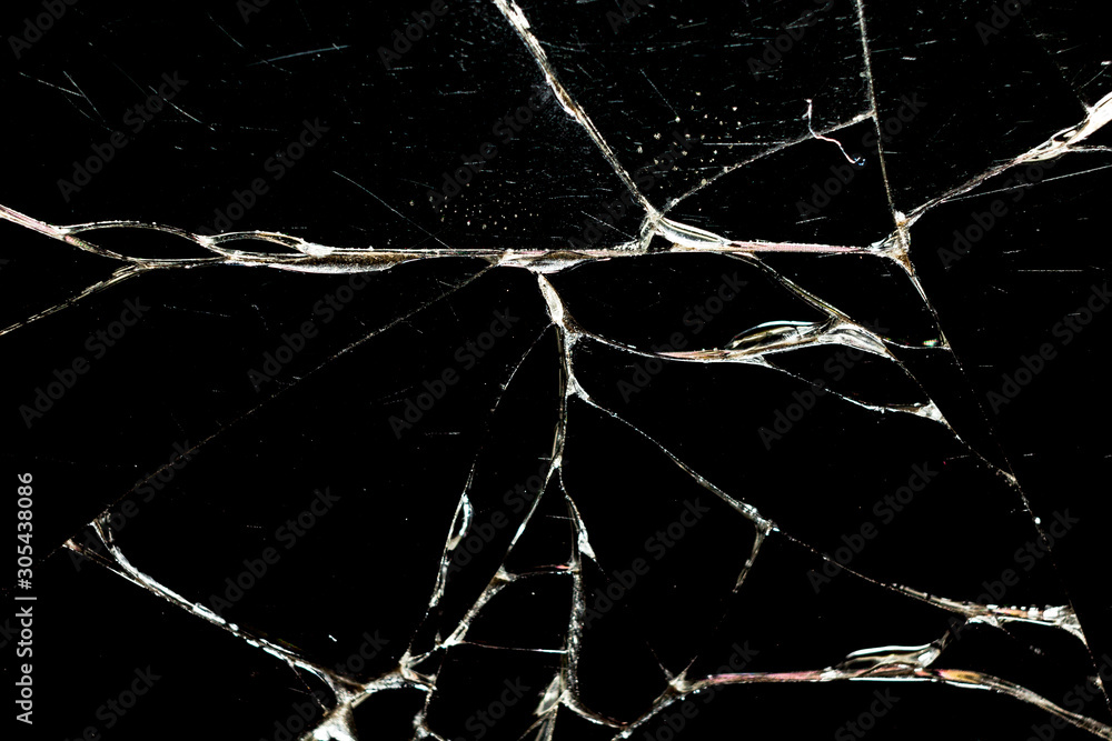 Realistic cracked glass texture on black background. The effect of broken glass. Harvesting. Close up.