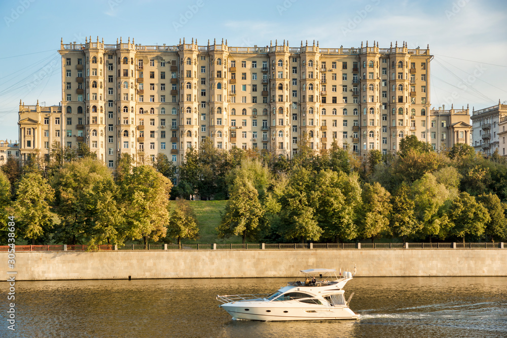 Moscow, Russia - June 15, 2019: a large house on the embankment of the Moscow River, a boat on the river
