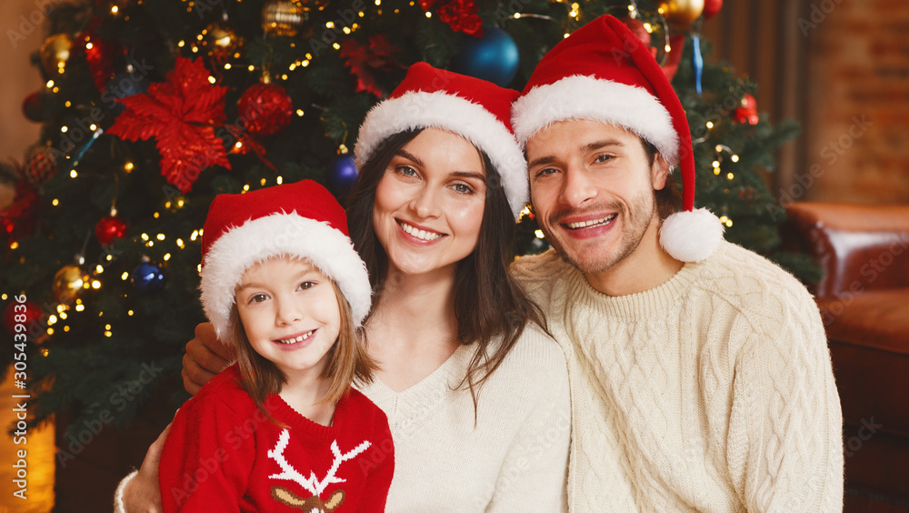Portrait of cheerful young family over Christmas tree Portrait of cheerful young family over Christmas tree