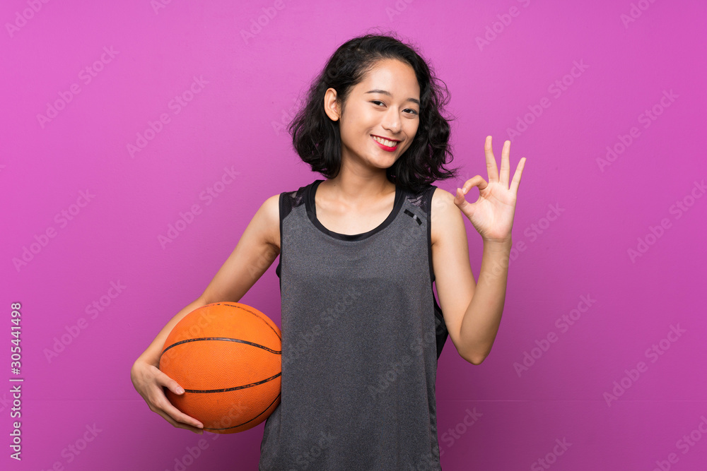 Young Asian woman playing basketball over isolated purple background Young Asian woman playing basketball over isolated purple background