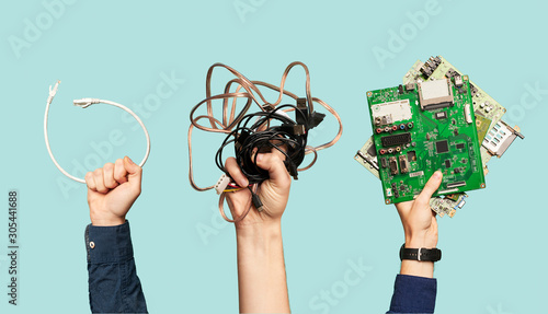 Three hands hold electrical waste on blank blue background. photo