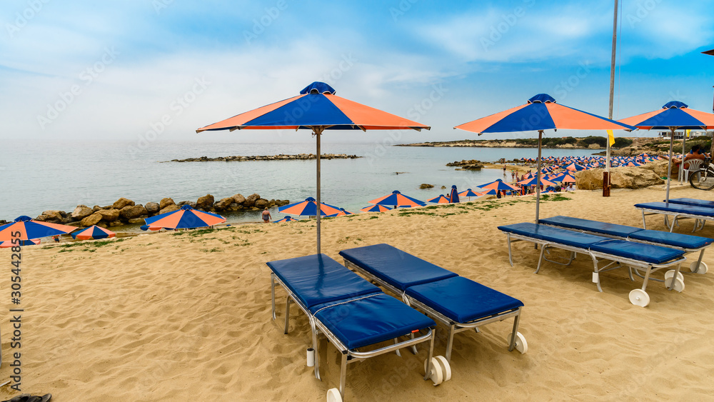 sun loungers on the beach of the mediterranean sea cyprus, new beach season, time to go on vacation