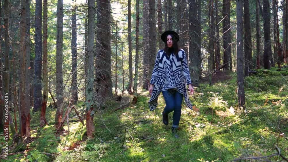 Girl walks in the autumn forest. yellow leaves. A blogger travels and we create new content. Sun rays. Authentic poncho and black hat. Ukrainian Carpathian Mountains. Girl walks in the autumn forest. yellow leaves. A blogger travels and we create new content. Sun rays. Authentic poncho and black hat. Ukrainian Carpathian Mountains.