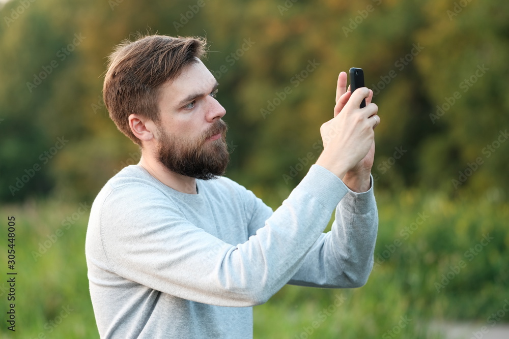 a man takes pictures on a cell phone. Mobile photography. Telephone addiction a man takes pictures on a cell phone. Mobile photography. Telephone addiction