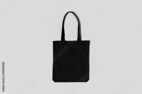 Black tote bag mockup on a grey background.